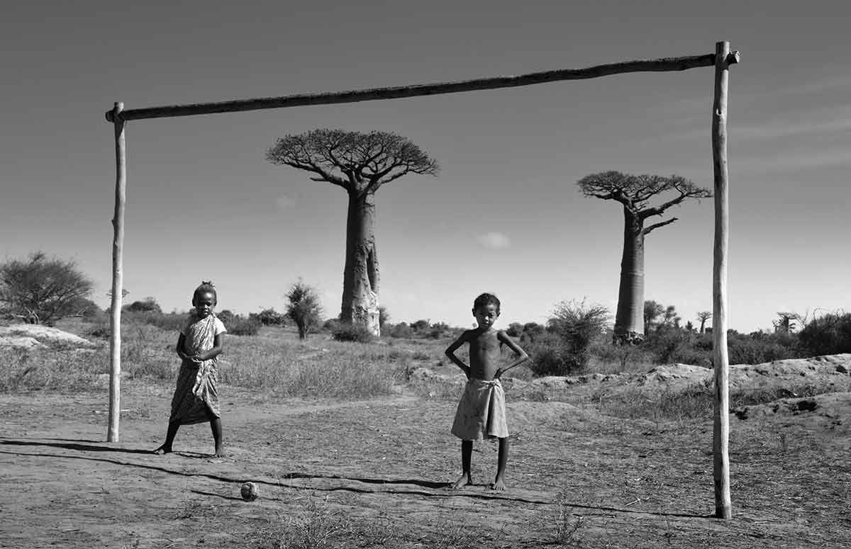 Deux enfant jouant au football devant l'avenue des baobabs à Madagascar